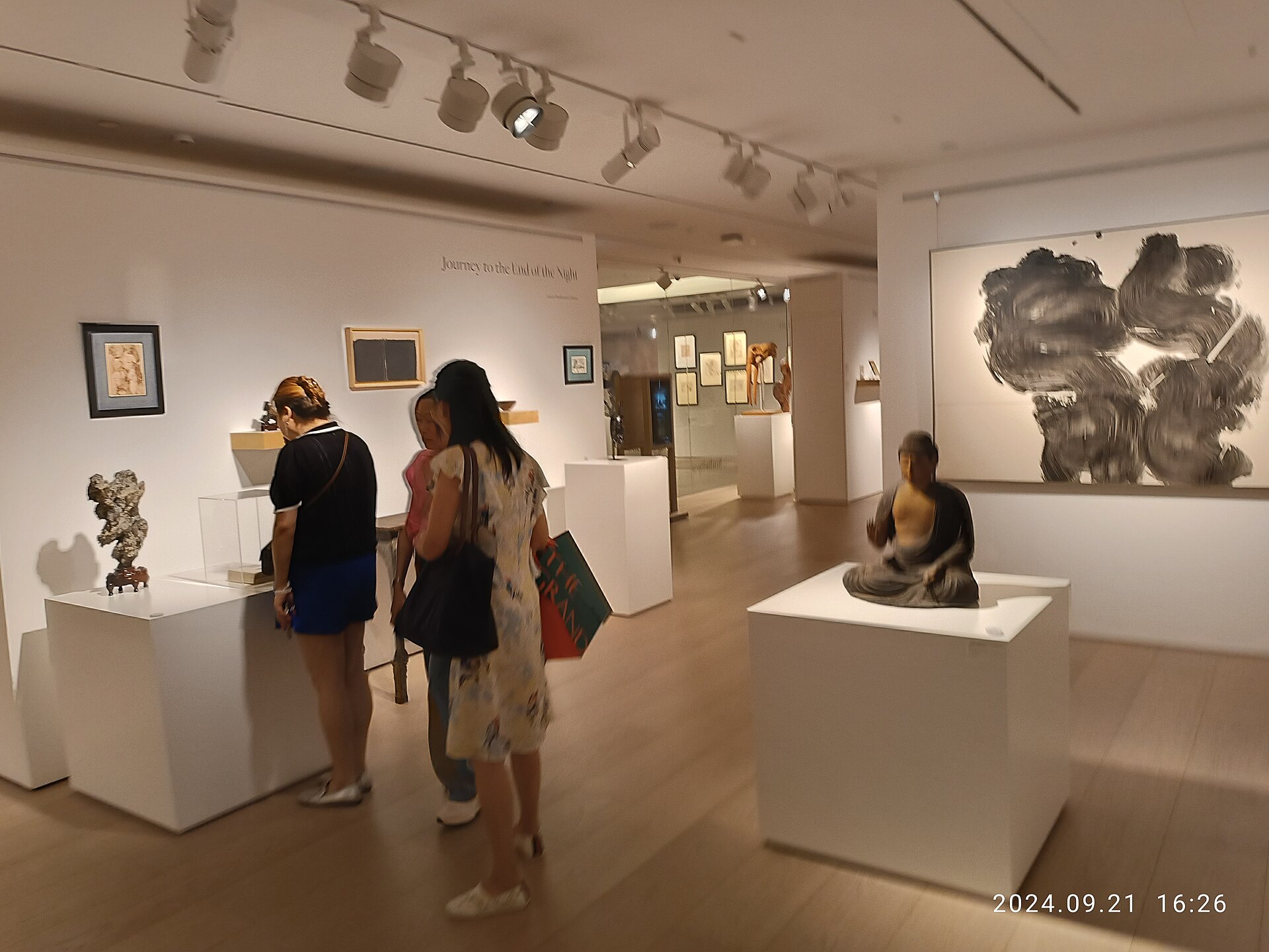 Vista de una sala de exposición previa a subasta con obras colgadas y visitantes recorriéndola.